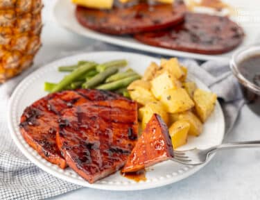 Cut piece of sweet teriyaki ham steak on a fork.