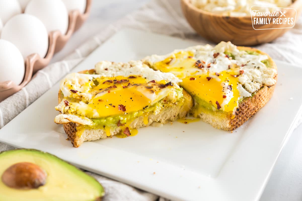 A feta egg on toast cut in half with the yolk dripping out