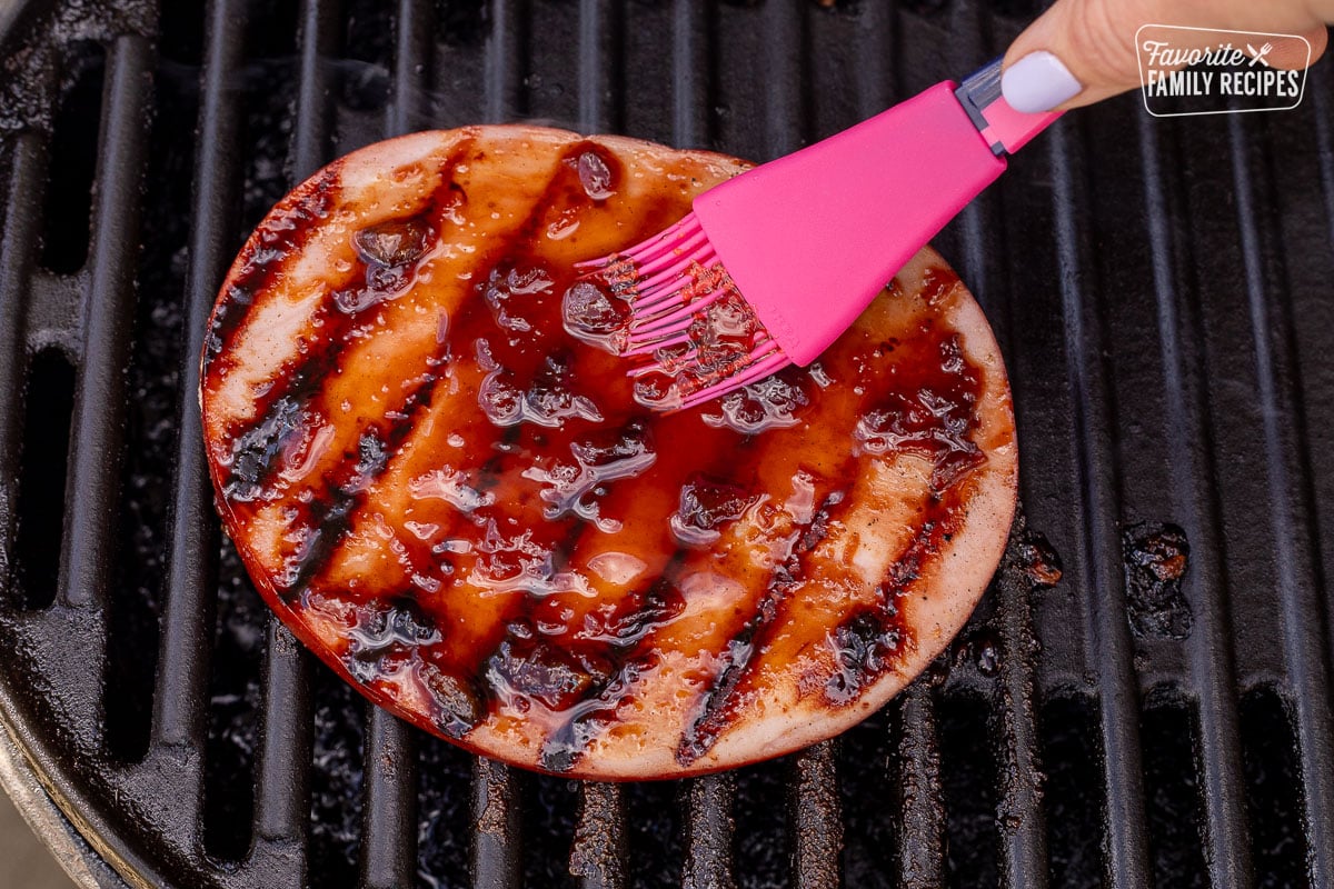 Brushing pineapple teriyaki sauce on barbecue ham steak.