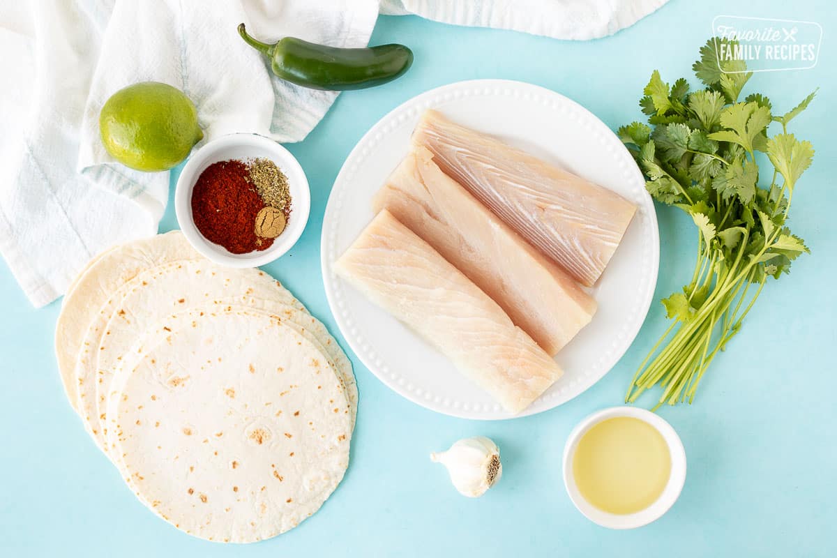 Ingredients to make Grilled Mahi Mahi Tacos including mahi mahi, cilantro, garlic, oil, spices, jalapeño, lime and flour tortillas.