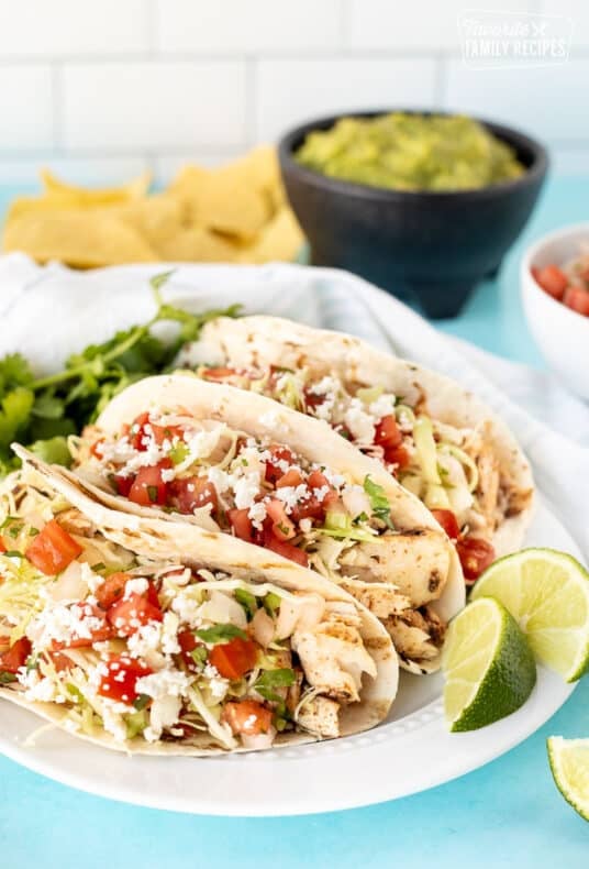 Grilled Mahi Mahi Tacos on a plate with limes and cilantro.