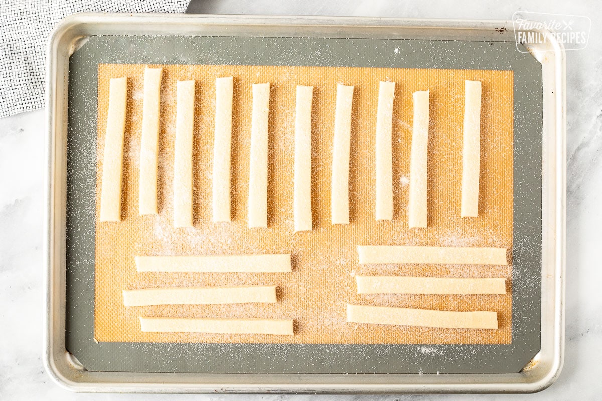 Cookie sheet mat with strips of sugar cookies topped with sugar.