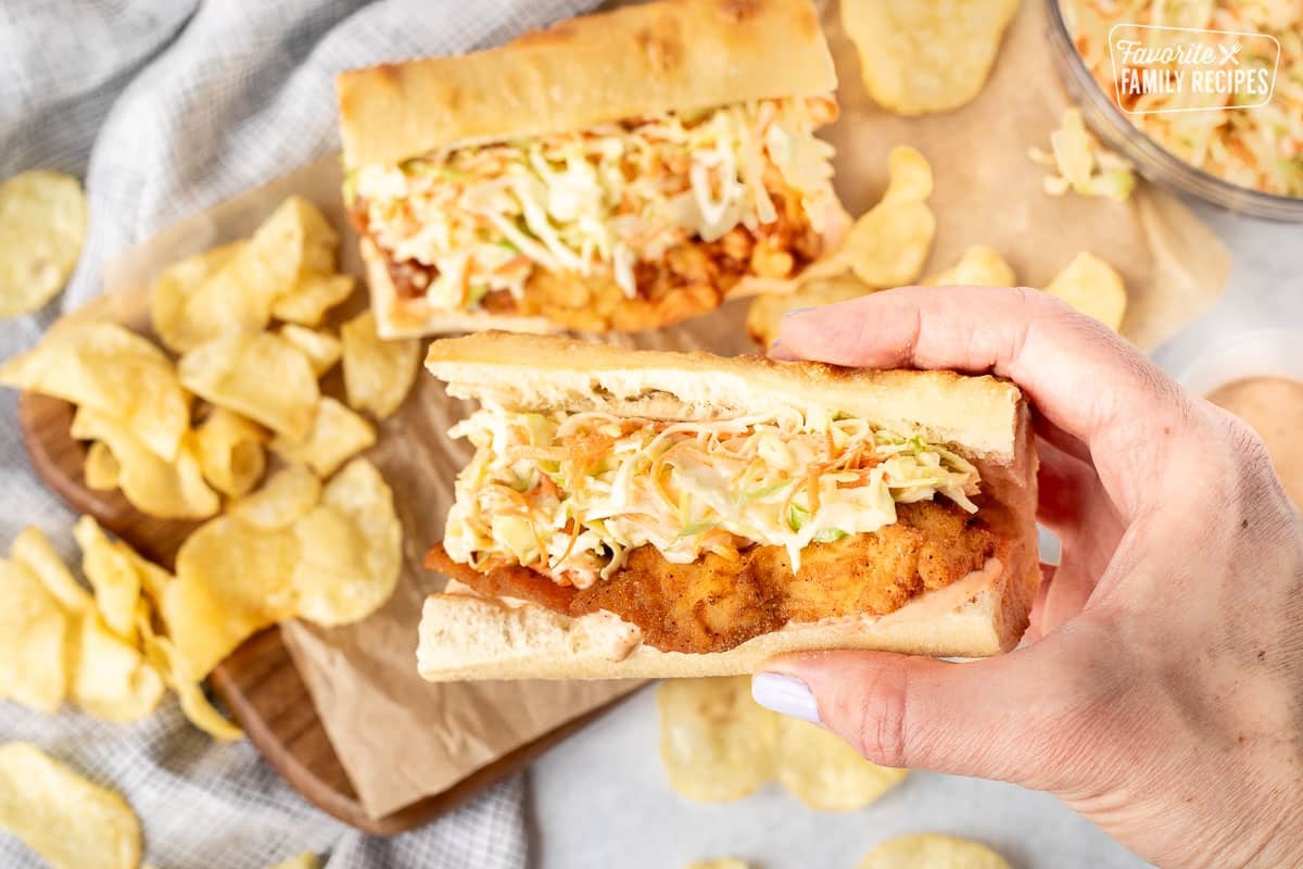 Hand holding up a Cajun Fried Chicken Po'Boy.