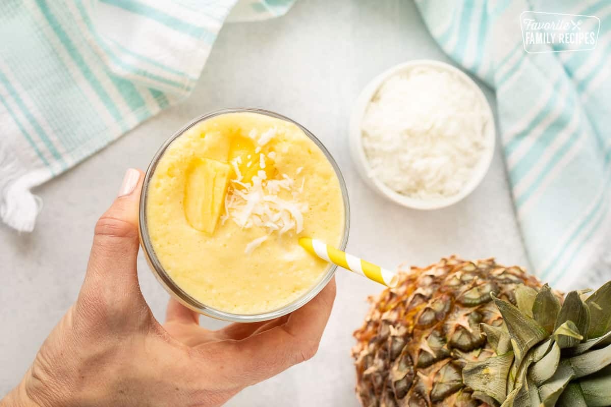 Hand holding a Pina Colada Smoothie in a glass.