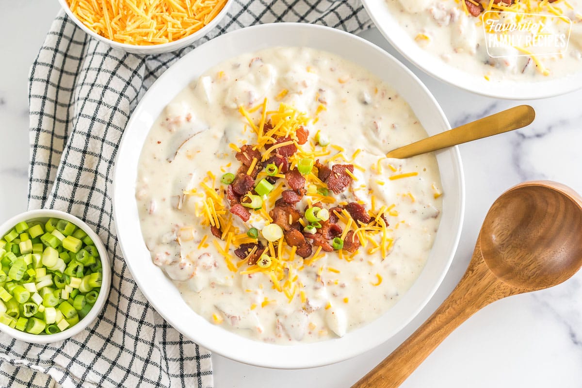 a bowl of loaded baked potato soup topped with bacon, cheese, and green onions