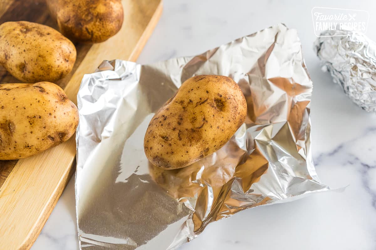 A potato getting wrapped in foil