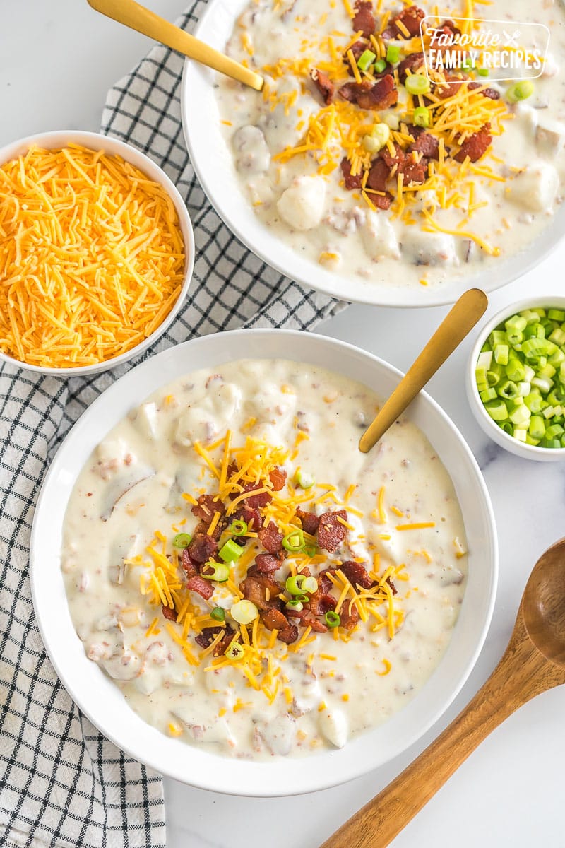two bowls of loaded baked potato soup topped with bacon, cheese, and green onions