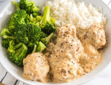 A bowl of Meatballs in Cream Sauce with broccoli and white rice