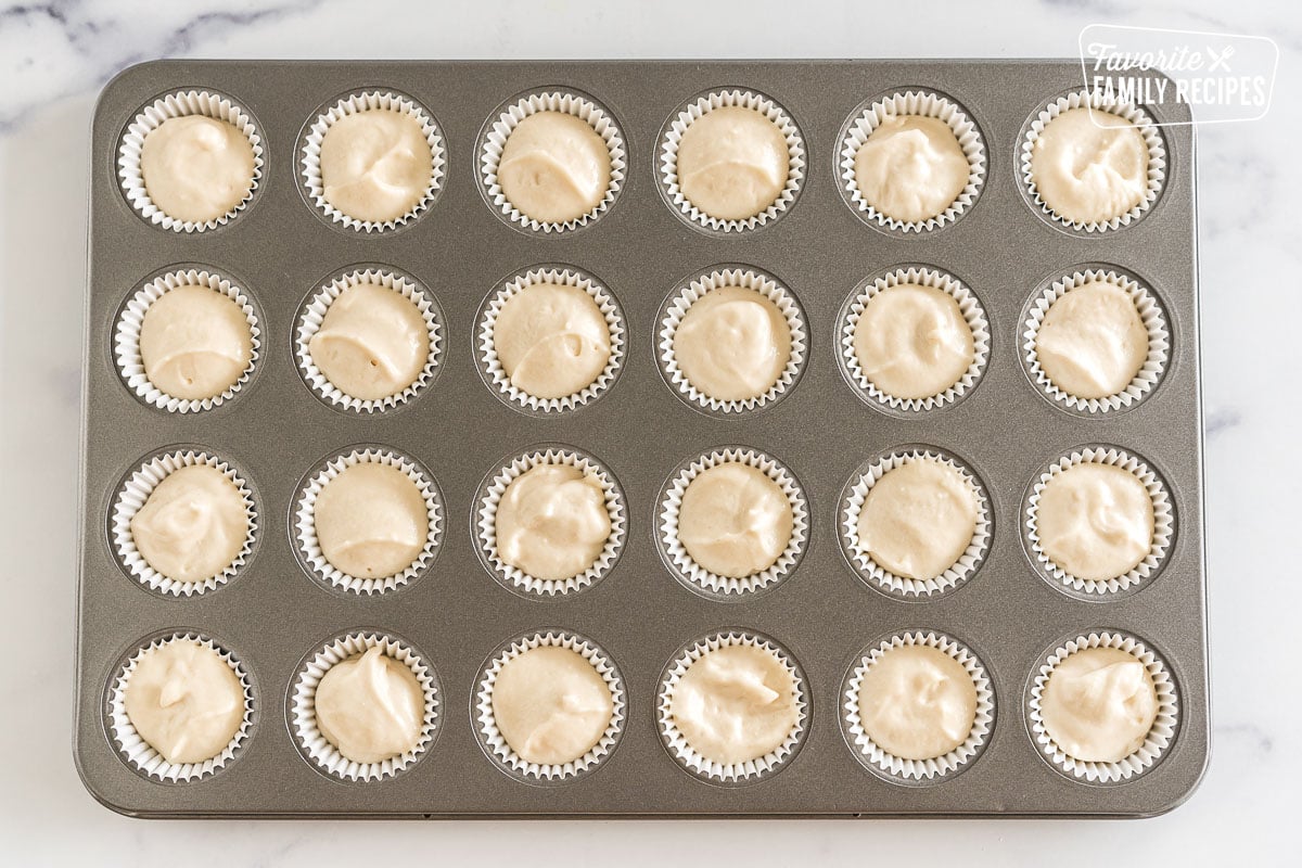 Vanilla cake batter scooped into a lined mini cupcake pan