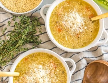 Two bowls of Pastina Soup topped with cheese and pepper