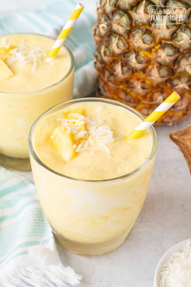 A sip of this Piña Colada Smoothie is an escape to a tropical hideaway. Loaded with pineapple and coconut, this smoothie is a refreshing and tasty treat. Close up of Pina Colada Smoothie in glasses with a straw.