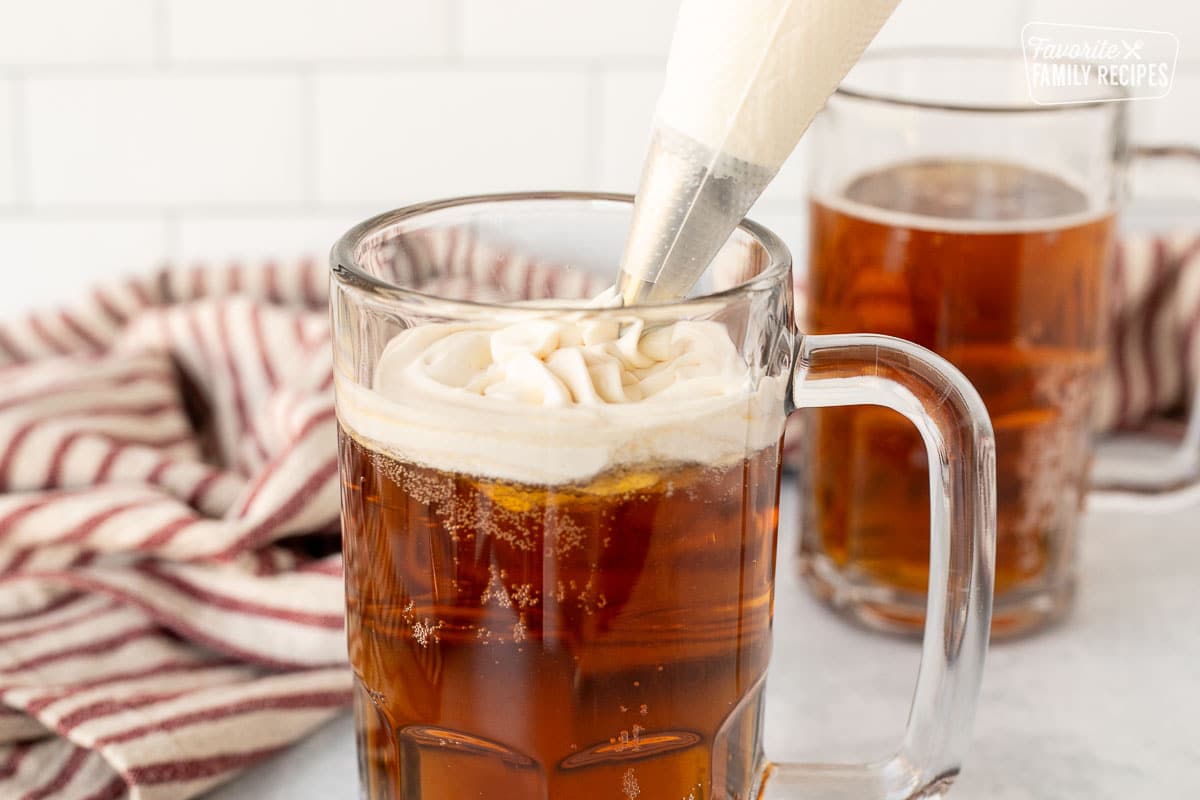 A glass of Butterbeer with flavored whipped topping piped on top.