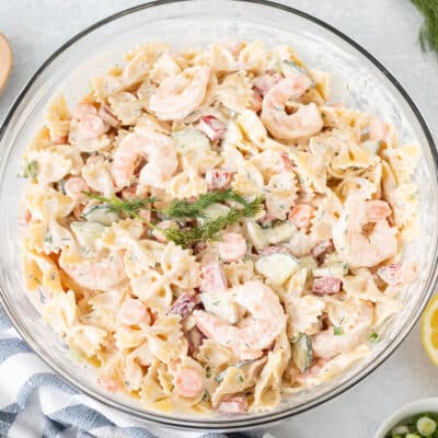 Shrimp Pasta Salad in a glass bowl with fresh dill and lemon on the side.
