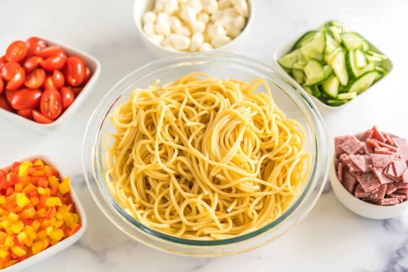a bowl of noodles surrounded by small bowls of toppings