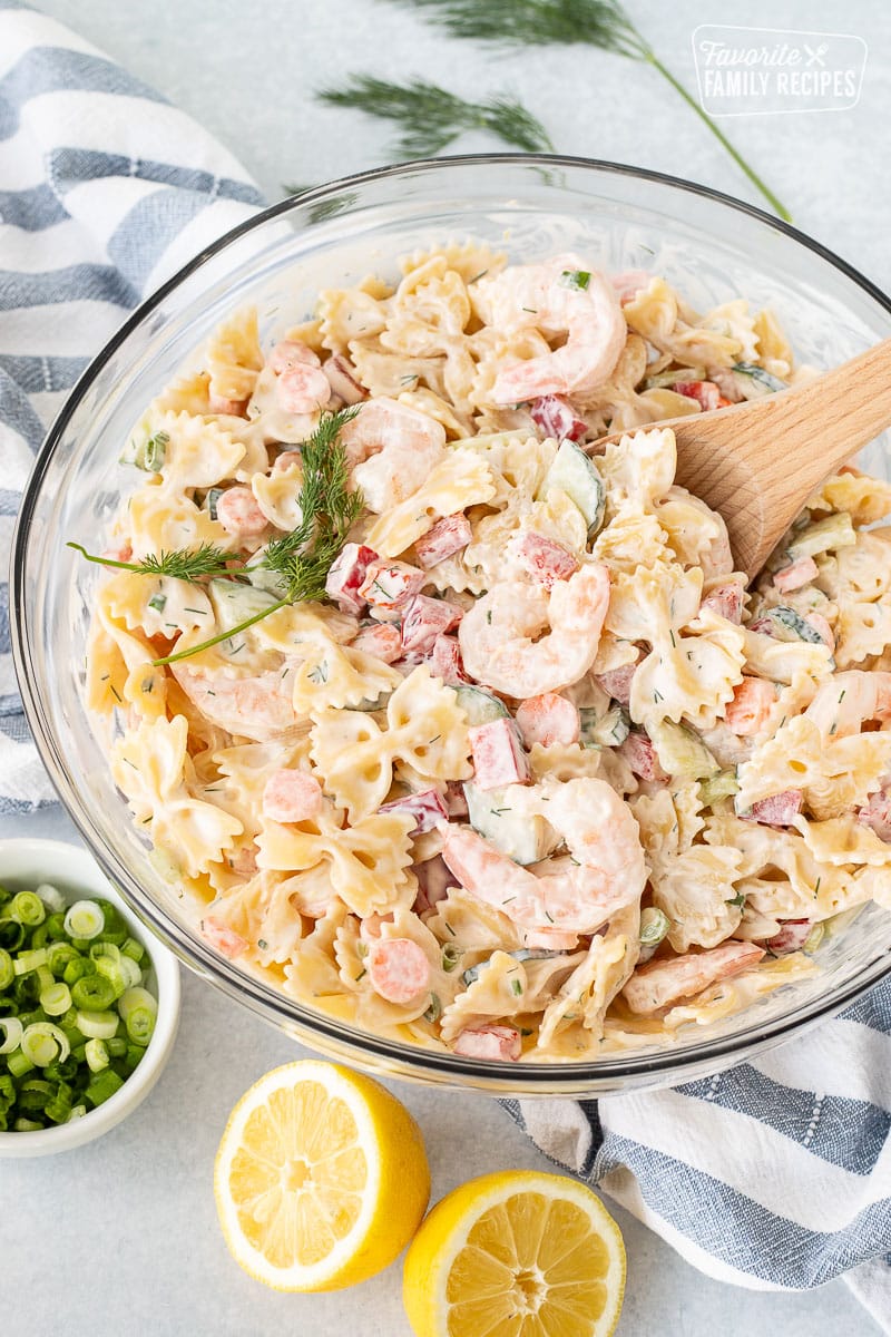 Wooden spoon resting in a bowl of Shrimp Pasta Salad.