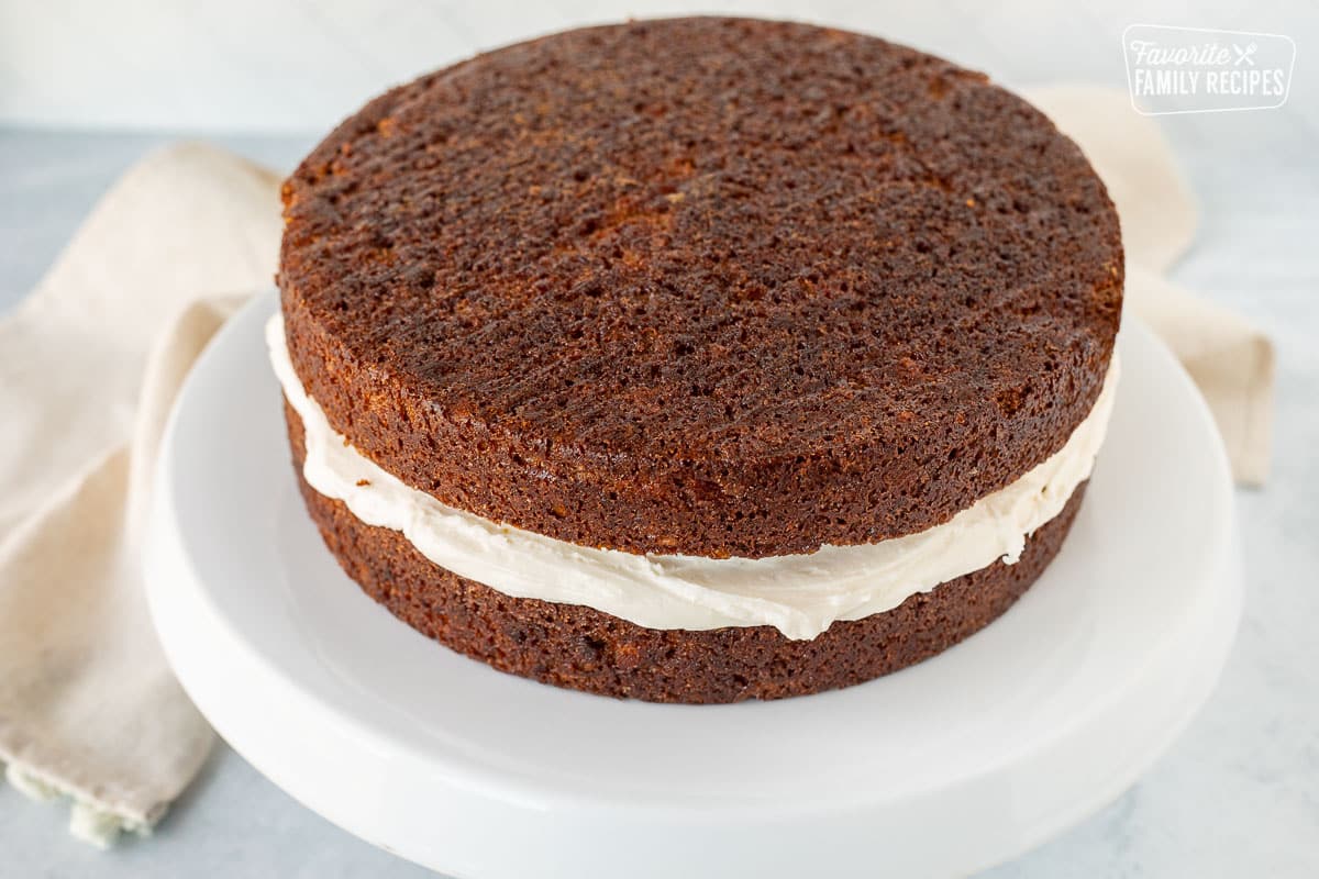 Two stacked carrot cakes with cream cheese frosting in the middle.