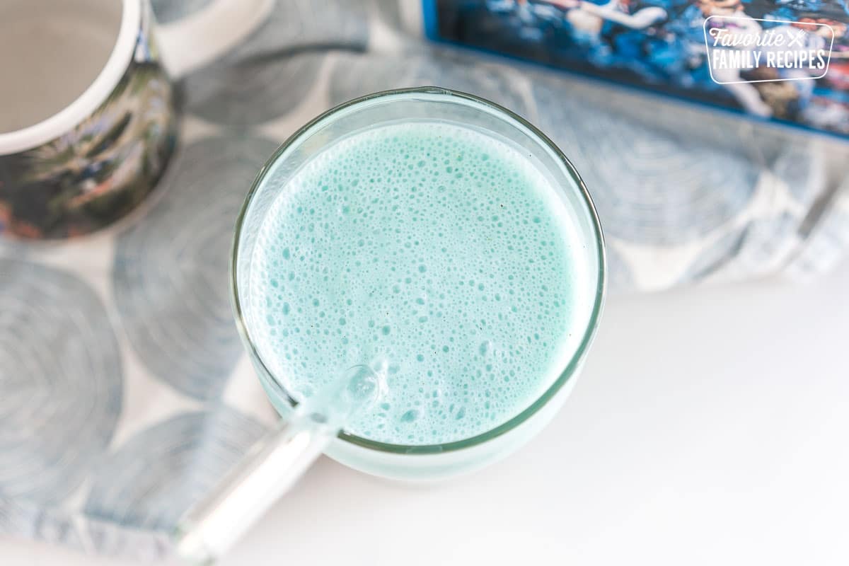 Frothy blue liquid in a tall glass with a straw