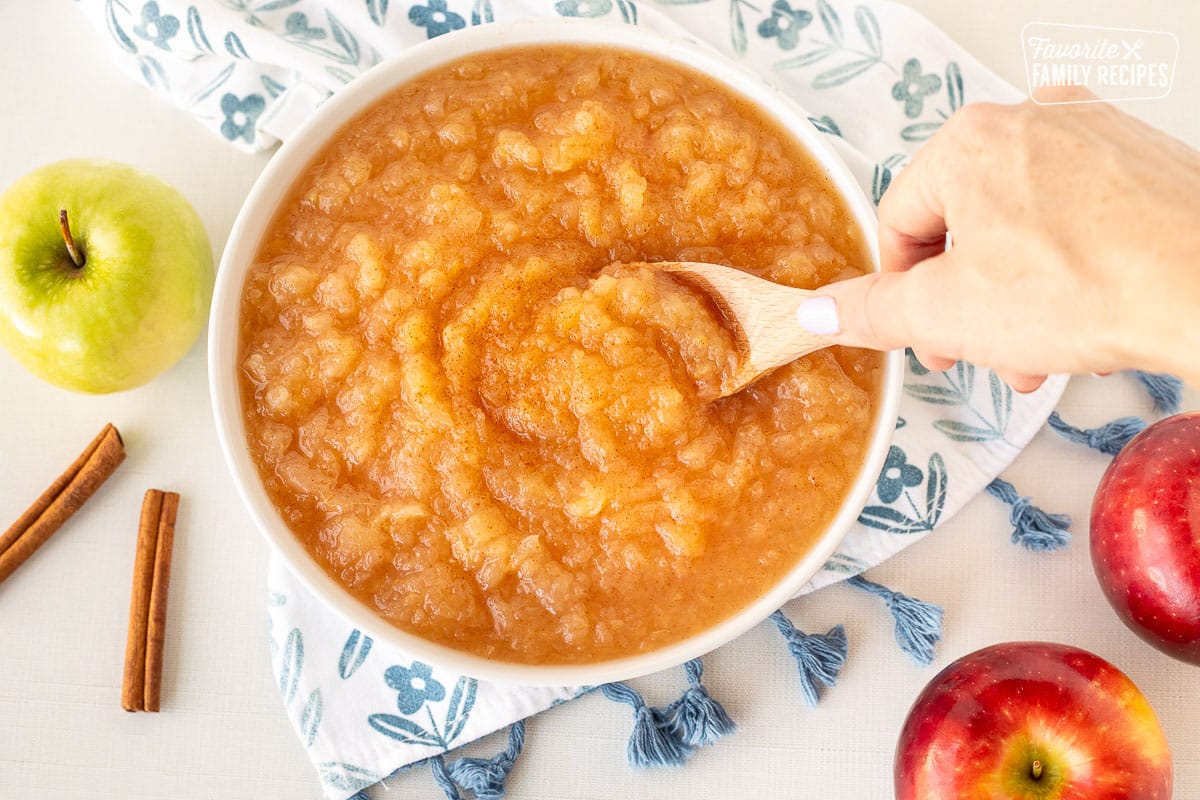 Scooping Instant Pot Applesauce with a wooden spoon.