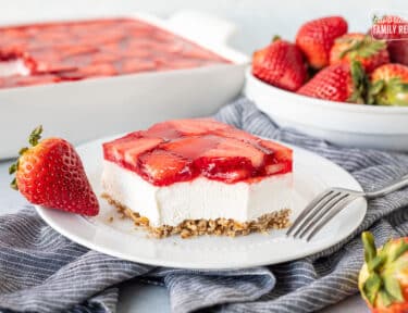 Plate with Strawberry Pretzel Salad with a fork and a fresh strawberry.