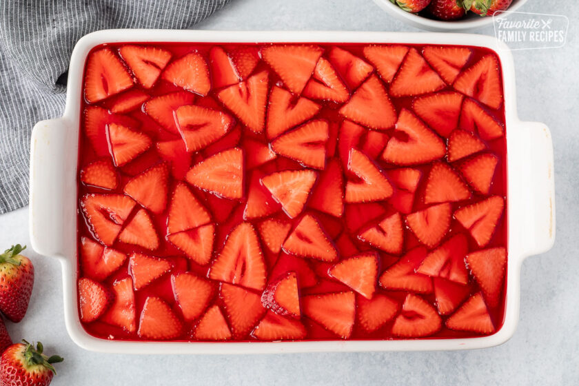 Strawberries and unset strawberry jello in a dish.