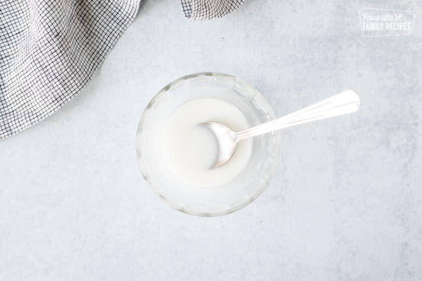 Small bowl of corn starch and water with spoon.