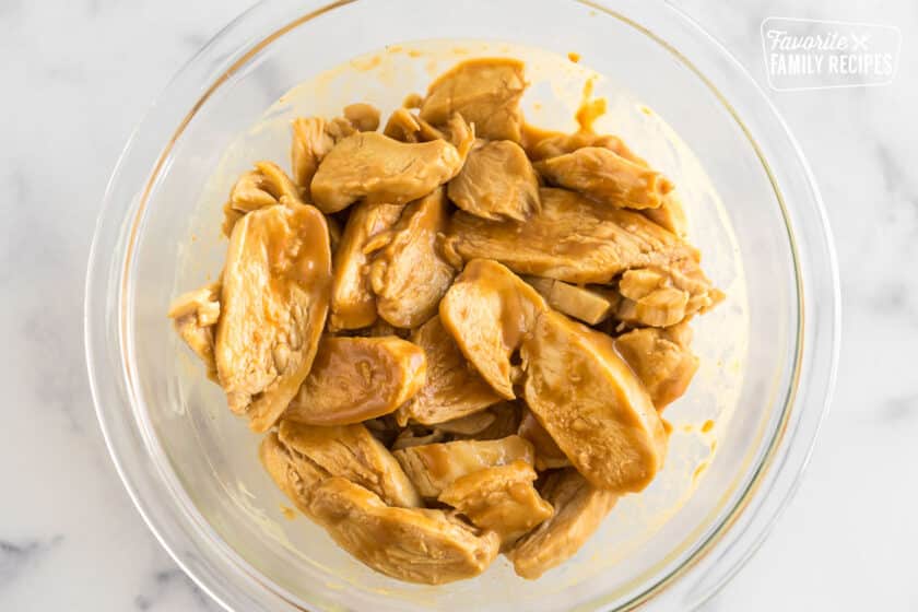 sliced chicken tossed with peanut sauce in a bowl