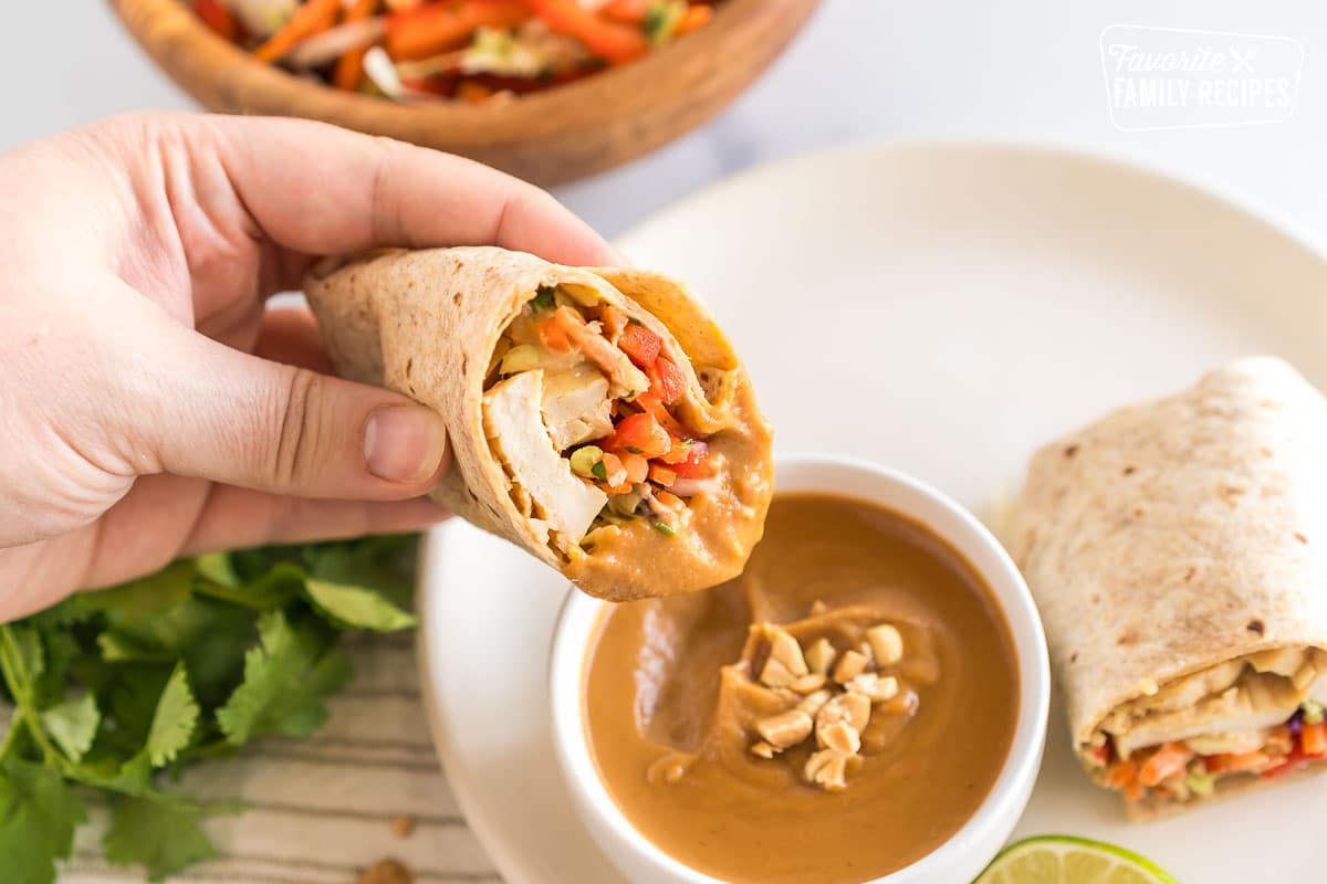 A thai chicken wrap dipped in peanut sauce