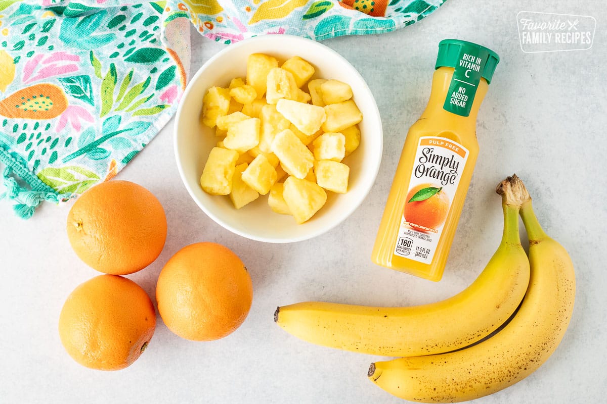 Ingredients to make Tropical Banana Smoothies including bananas, orange juice, frozen pineapple and oranges.
