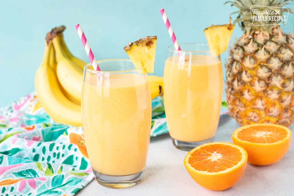 Two glasses of Tropical Banana Smoothies with fresh pineapple and straws.