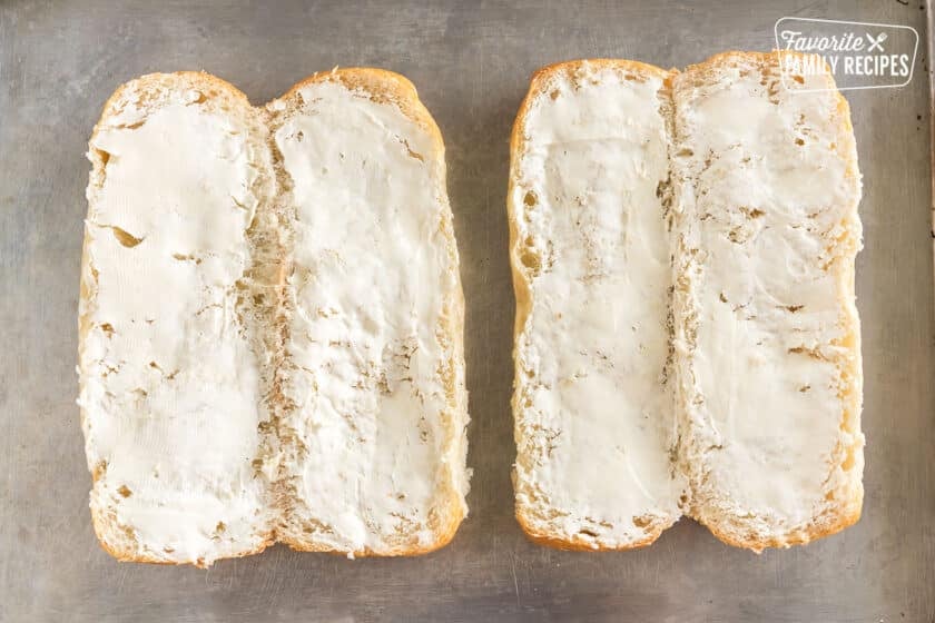 Two sub rolls sliced open and spread with cream cheese