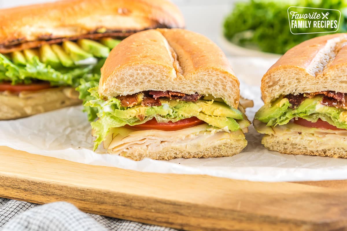 A Turkey Bacon Avocado Sandwich cut in half on a cutting board