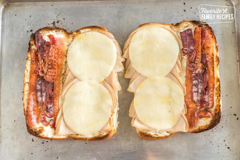 Two sub rolls sliced open and spread with cream cheese, meat, and provolone cheese. Toasted.