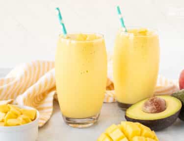 Two glasses of Mango Avocado Smoothie with straws.