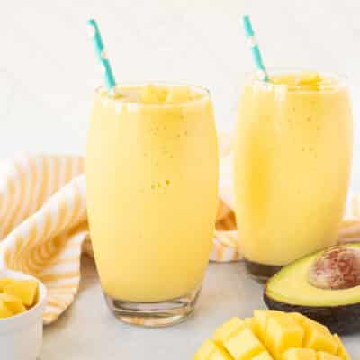 Two glasses of Mango Avocado Smoothie with straws.