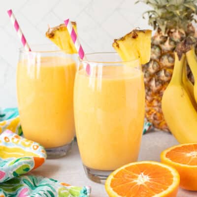 Tropical Banana Smoothies in glasses garnished with fresh pineapple.