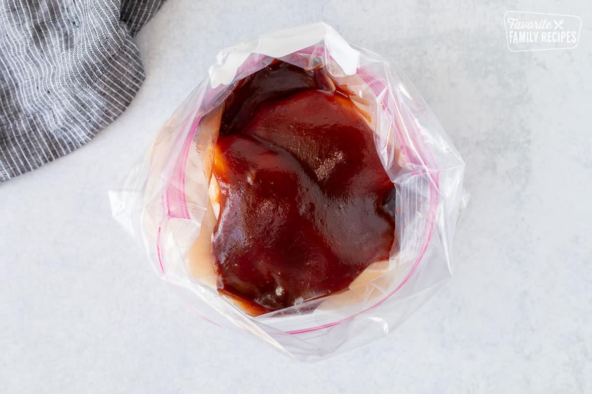 Ziplock bag with chicken breasts covered in barbecue sauce.