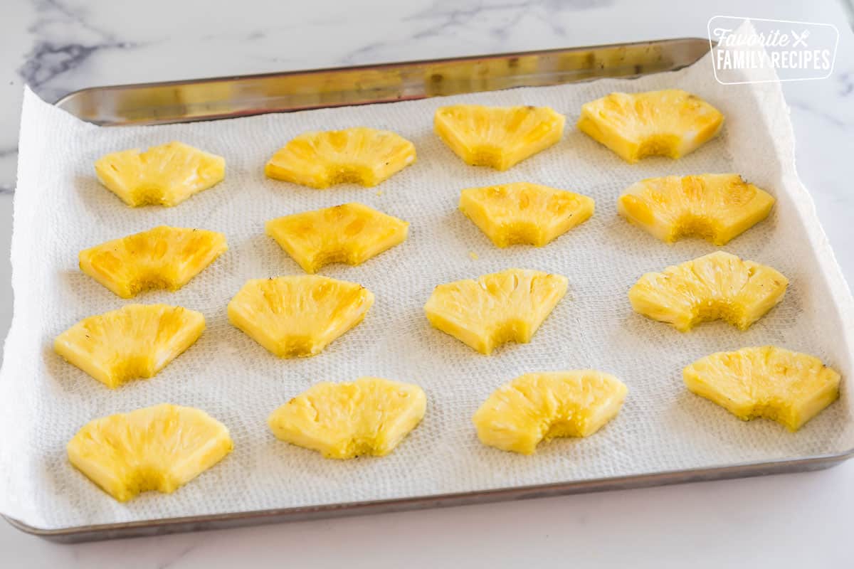 wedges of pineapple on a paper towel lined baking sheet