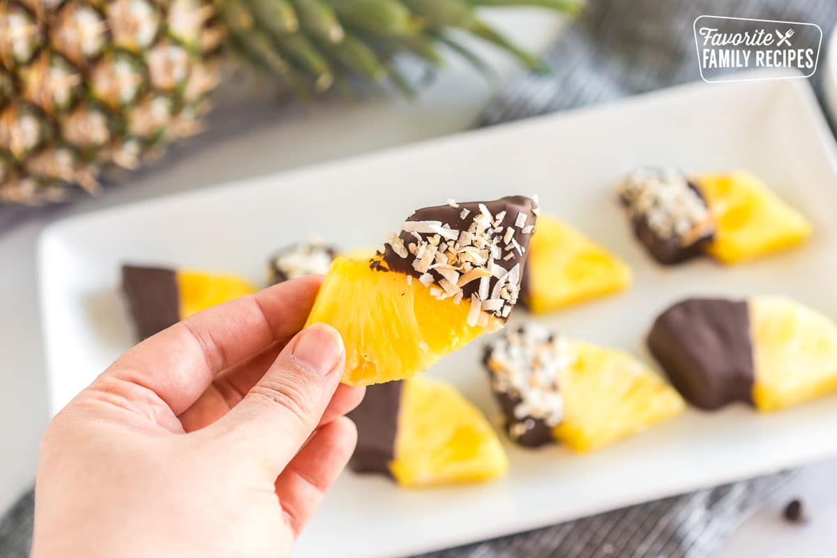a wedge of pineapple dipped in chocolate and sprinkled with toasted coconut