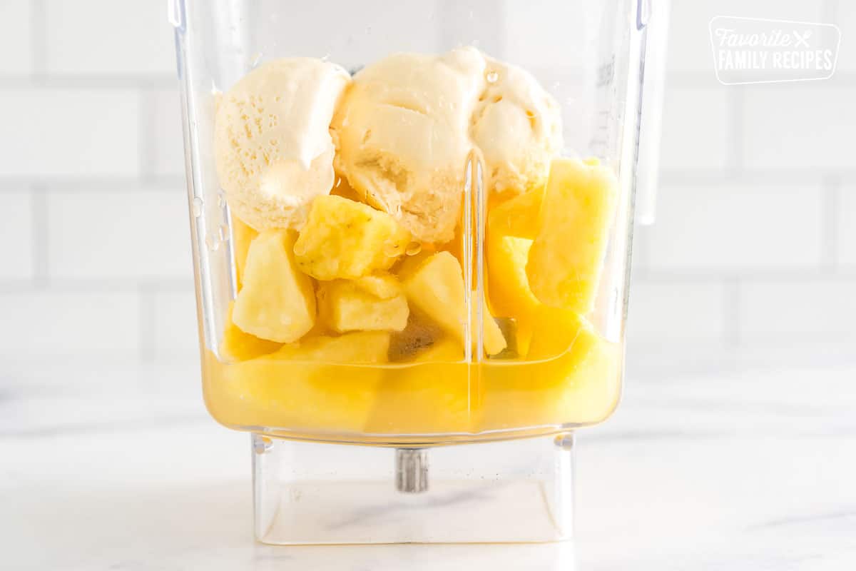 A blender full of pineapple juice, frozen pineapple, vanilla ice cream and lemon juice