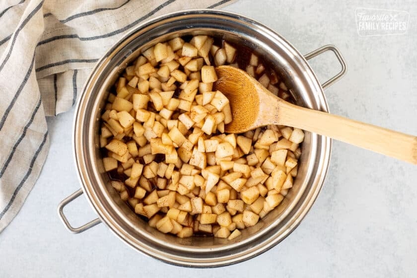 Saucepan with sliced pears and seasonings. Wooden spoon resting in the pan.