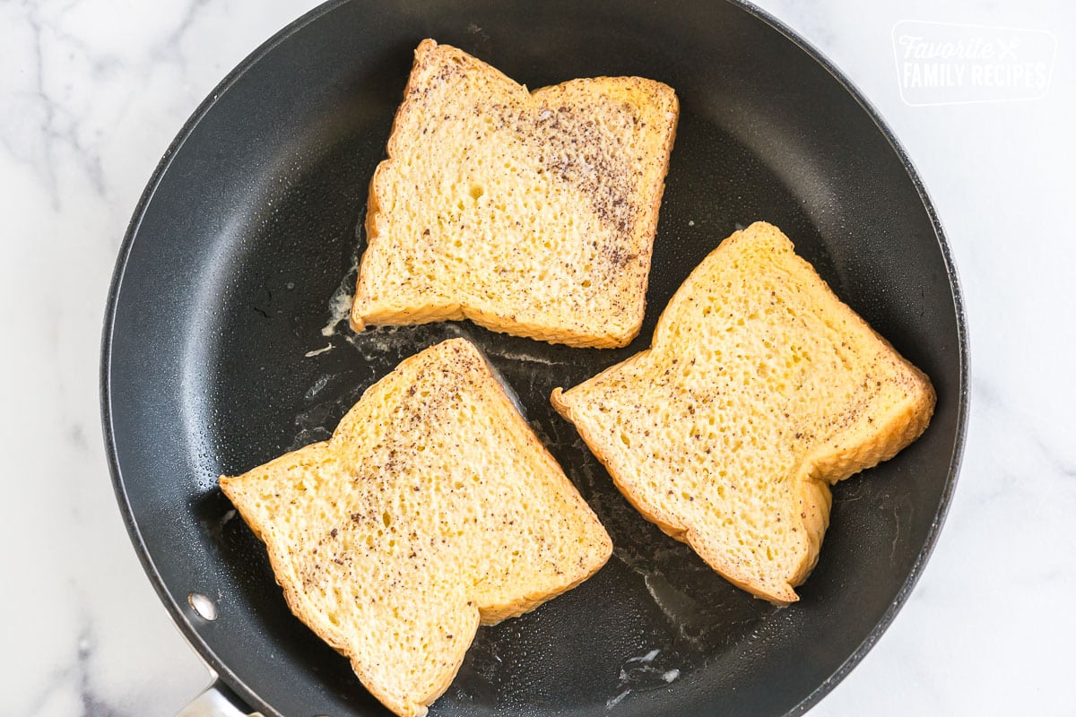three pieces of bread cooking in a skillet