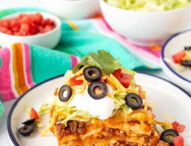 Plate with a piece of Mexican Lasagna with taco toppings.