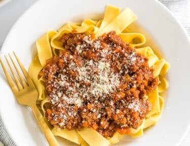 A bowl of Pappardelle Bolognese topped with parmesan cheese