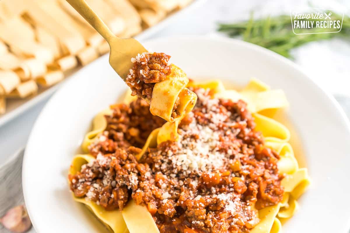 A fork taking a bite of pappardelle bolognese