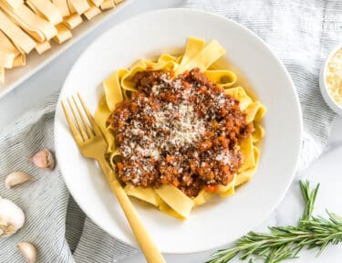 A bowl of Pappardelle Bolognese topped with parmesan cheese