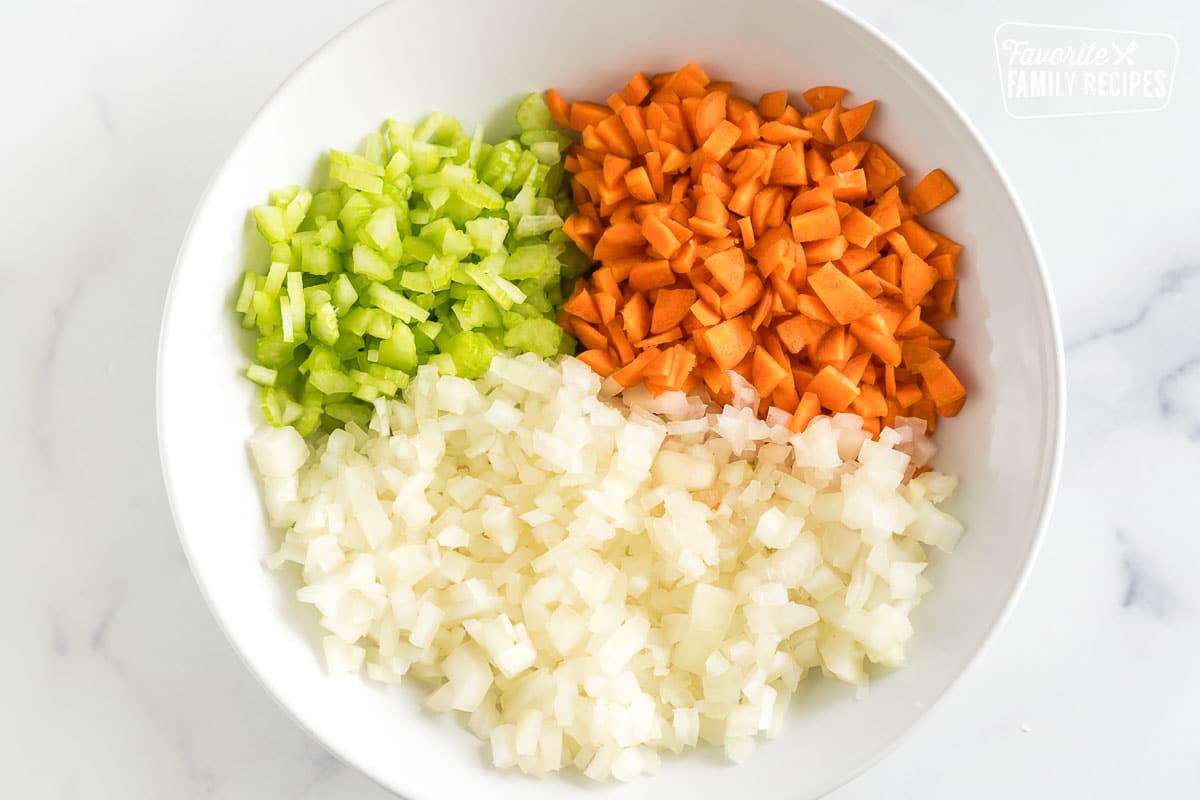 Onion, celery, and carrots diced in a bowl