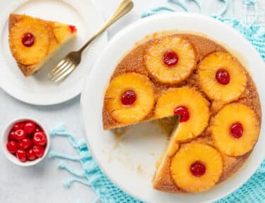 Cake stand with Pineapple Upside Down Cake missing a slice. Slice of Pineapple Upside Down Cake on a plate.
