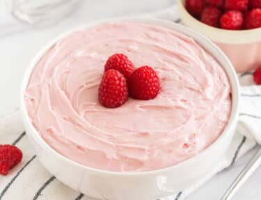 Raspberry Frosting in a bowl topped with raspberries