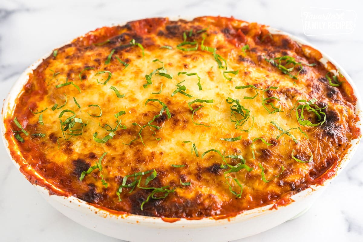 Baked ravioli lasagna with a melted cheesy layer on top, topped with basil