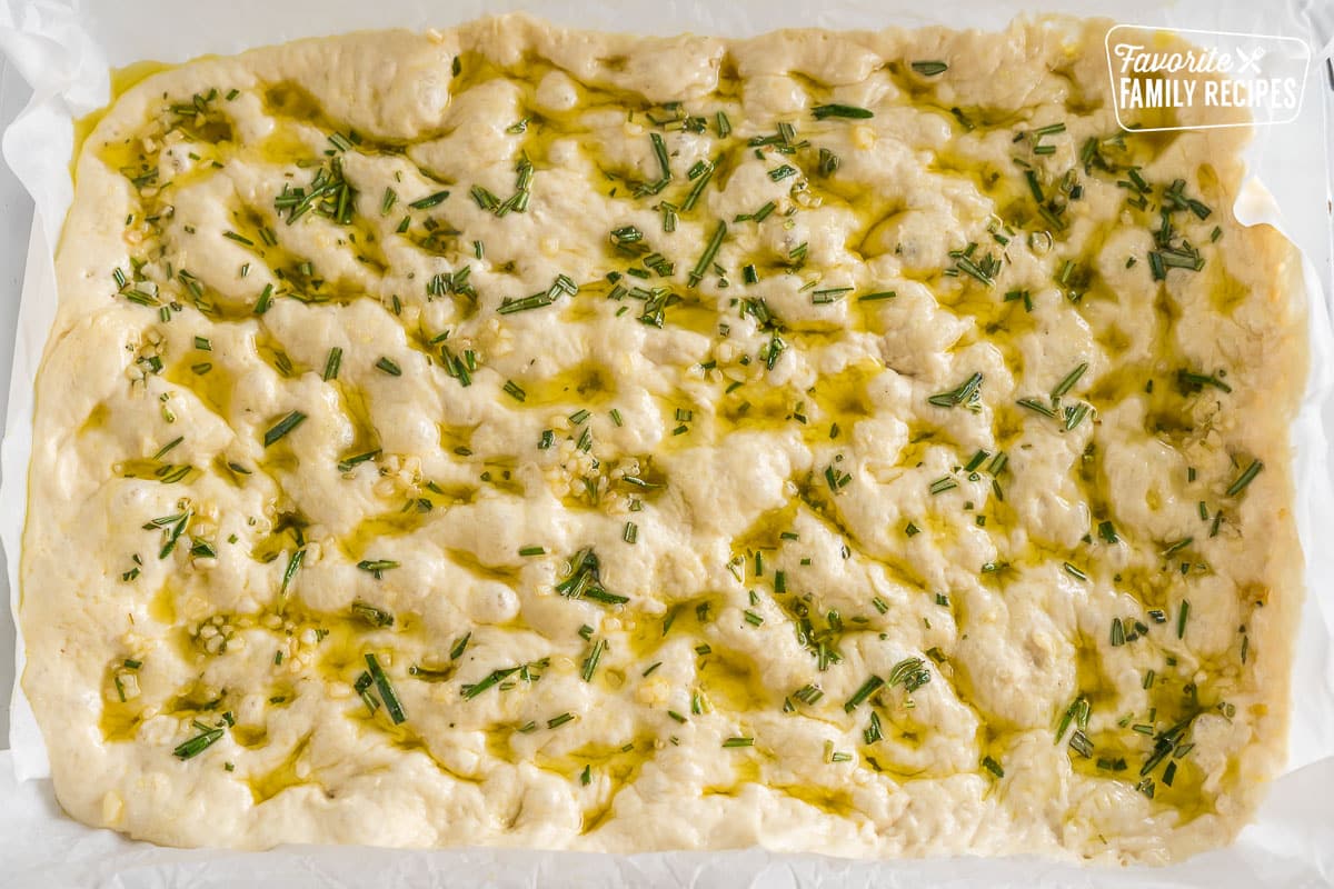 Dough in a pan drizzled with herb infused olive oil